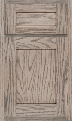 Shiloh Hanover, A wooden cabinet door from Bethesda Cabinets features a recessed center panel and visible wood grain in a light, weathered gray finish. The rectangular frame creates a classic, rustic look
