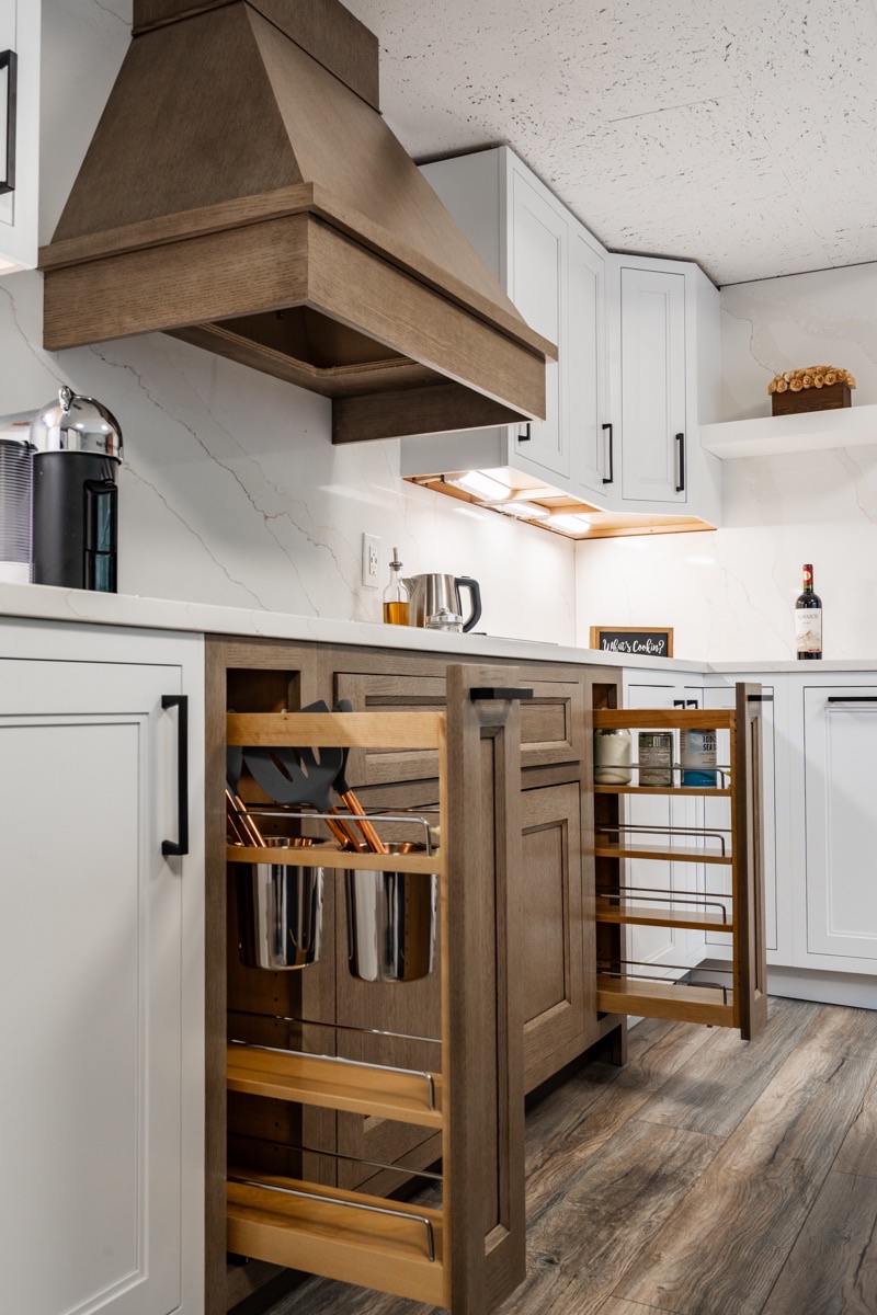 Kitchen display at the Bethesda Cabinets showroom with white cabinets, a wood range hood, and a marble island.