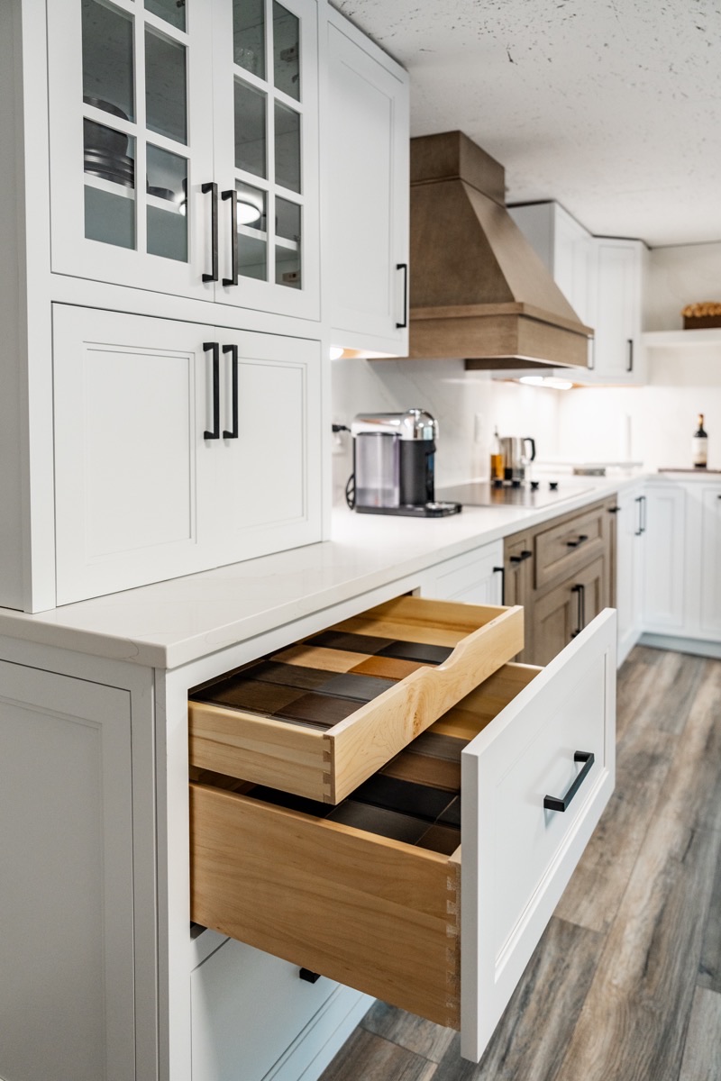 Kitchen display at the Bethesda Cabinets showroom with white Shiloh cabinets and an open wood storage drawer.