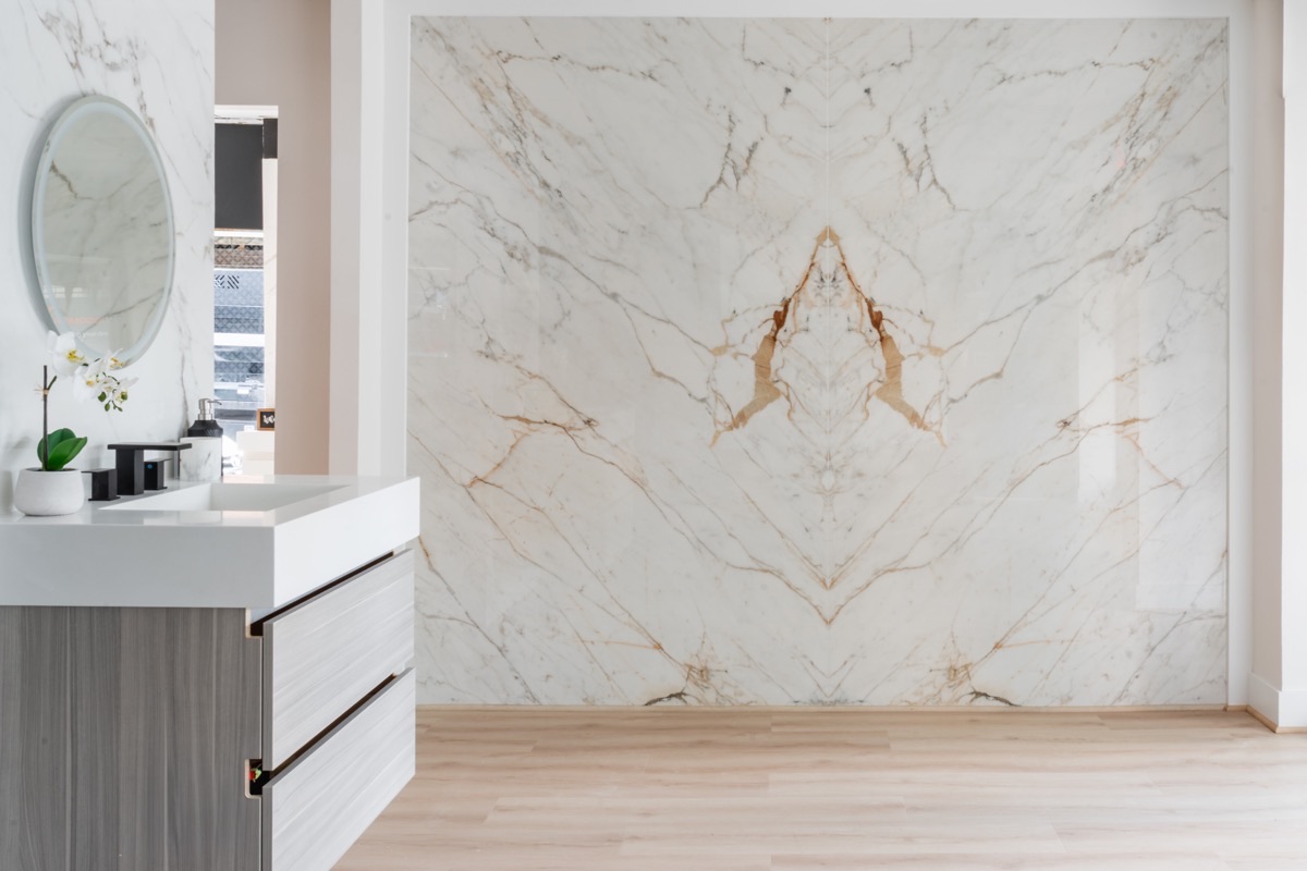 Bathroom vanity display at the Bethesda Cabinets showroom with a book-matched marble slab wall and drawer storage below.