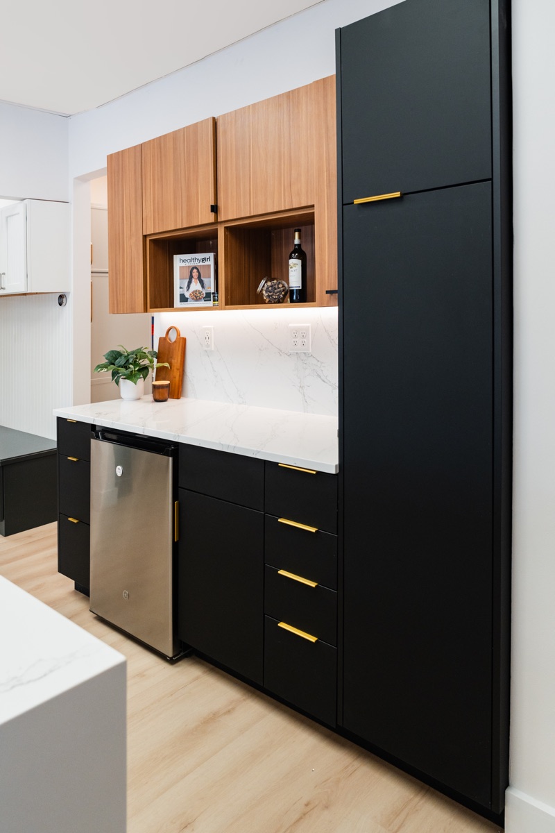Kitchen display at the Bethesda Cabinets showroom with black cabinets, a marble countertop, and open wood shelving.