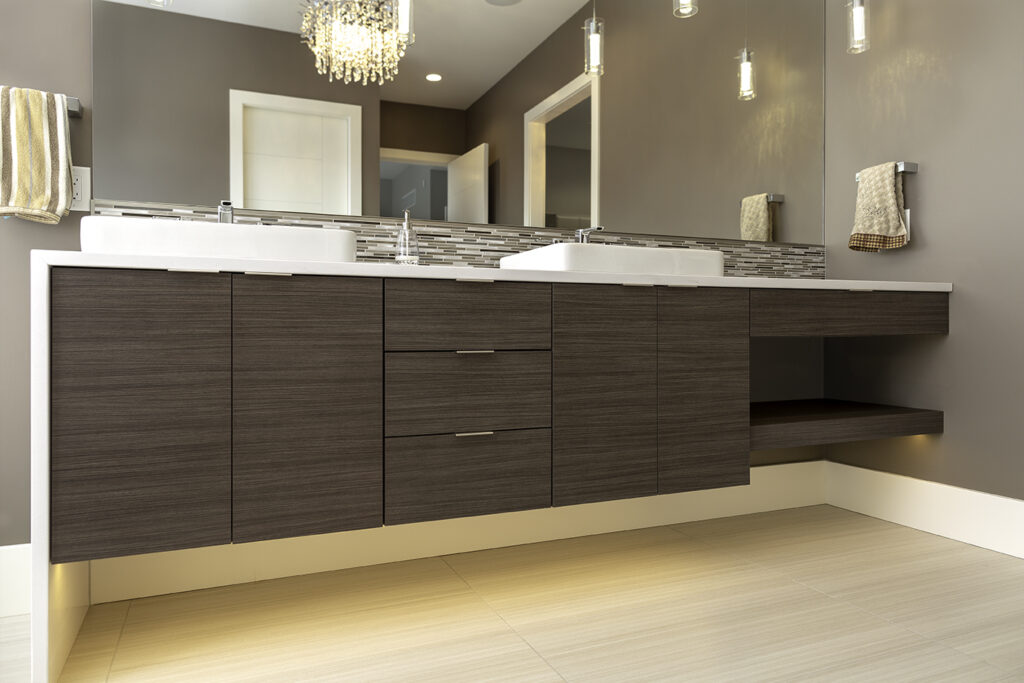 Modern bathroom with a floating wooden vanity, double sinks, a large mirror, pendant lights, and neutral-colored walls and floor tiles. A striped towel hangs on the left and a brown towel on the right.