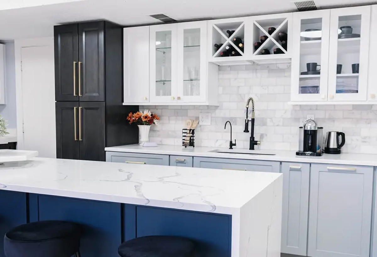 Kitchen display at the Bethesda Cabinets showroom with navy and white cabinets, a marble island, and glass-front display cabinets.