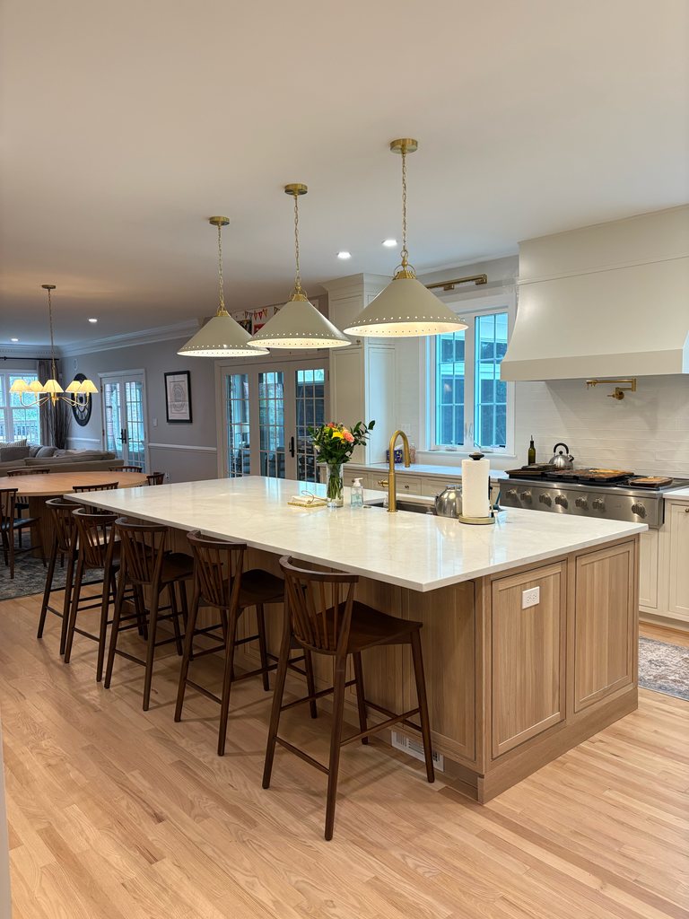 Shiloh inset cabinetry in soft white with a long white oak island, MSI quartz countertops and three pendant lights over the island, a Bethesda Cabinets project.