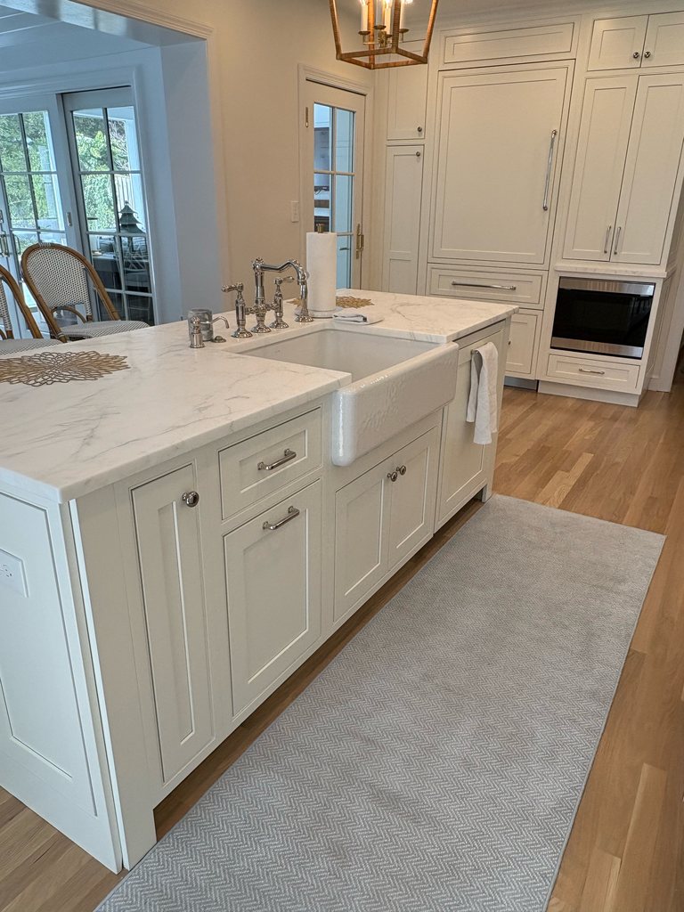 White island with a quartzite countertop and a farmhouse sink, in front of a paneled refrigerator wall and a built-in microwave in Shiloh beaded inset cabinetry, soft white, a Bethesda Cabinets project.
